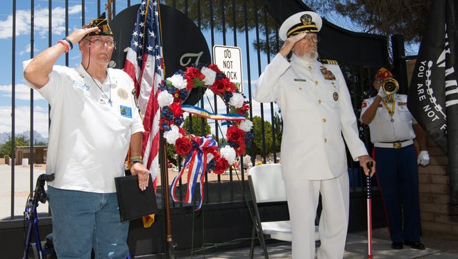 American Legion Post 10 chaplin Lawrence Orvis, left, and Ret. Navy Captain Walt Baker stand at attention and salute  as bugalist Raymond Rivera plays the trumpet.