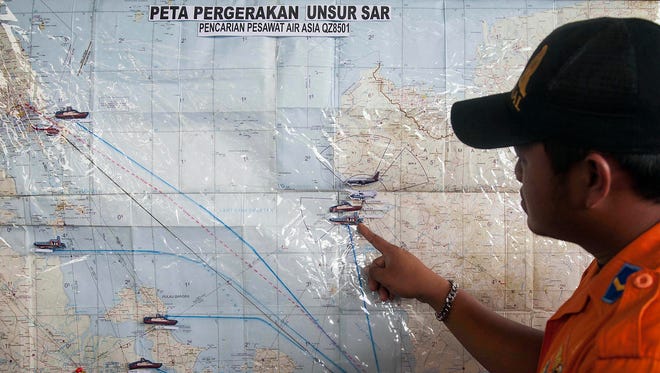 A search and rescue officer points to a co-ordination map of Indonesia at the crisis center set up by local authorities in search of the missing AirAsia flight QZ8501 at Juanda International Airport in Surabaya, East Java, Indonesia, Monday, Dec. 29, 2014.