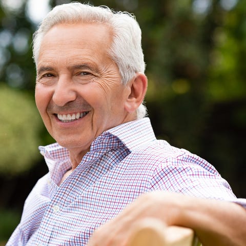 Smiling senior man sitting on a bench outdoors.