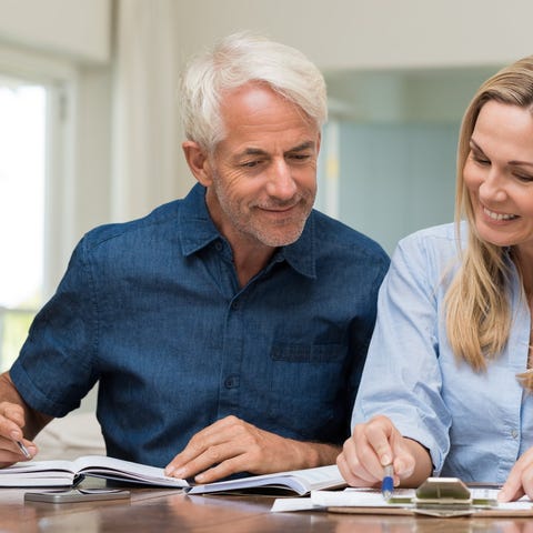Mature couple smiling and looking at documents.