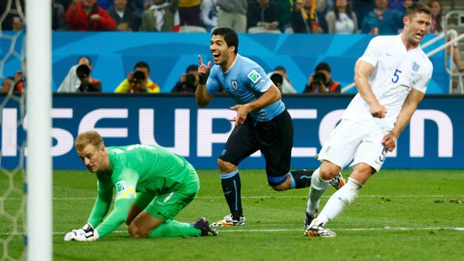 
England’s Gary Cahill (right) and Joe Hart (left) react as Uruguay’s Luis Suarez celebrates his goal during their World Cup Group D match Thursday in Sao Paulo.
