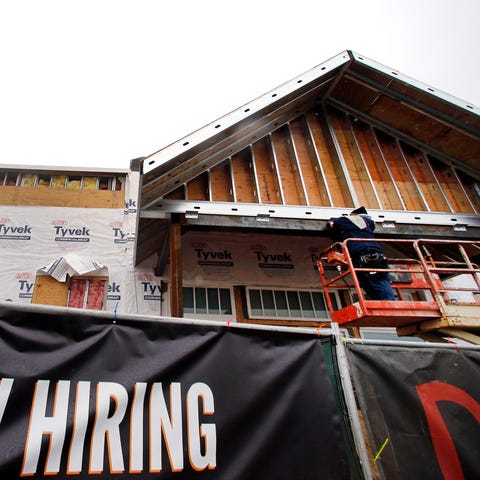 Aa now hiring sign hangs nearby as a builder works