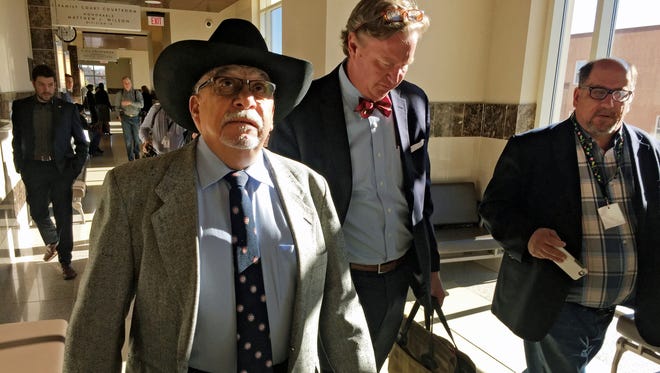 In this April 4, 2016, file photo, former New Mexico state Sen. Phil Griego, left, and his attorney Tom Clark, center, walk out of an arraignment in Santa Fe District Court in Santa Fe, N.M. Griego, a Democrat who is accused of using his former position as a lawmaker and his acumen as a real estate broker to profit from the sale of a state-owned building in downtown Santa Fe via complex interactions with a state agency, allied lawmakers and a public buildings commission, goes on trial next week on corruption charges in a high-stakes showdown with state prosecutors.
