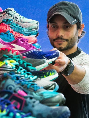Run Culture owner Carlos Rivas, is pictured with a large selection of running shoes avaible at his store,  located at 221 N. Main St., on Friday, Jan. 26, 2016.