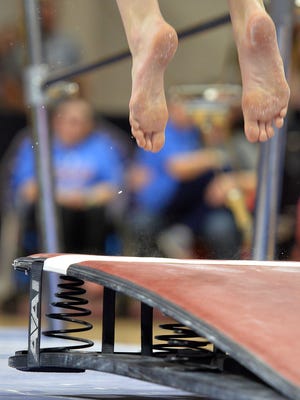 A gymnast performs on the uneven parallel bars during the state high school gymnastics meet in 2016.