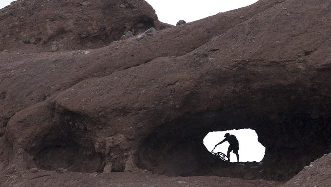 A biker takes shelter from the rain in Hole-In-The-Rock on Sept. 29, 2016, at Papago Park in Phoenix.