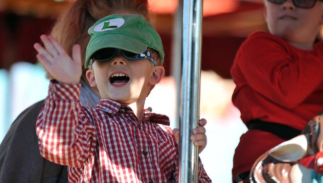 Wyatt Pierce, 4, of Deerfield, waves to his dad from the carousel while riding at the Deerfield Harvest Festival on Sunday.