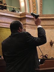 Rep. Charles Young displays his gun during debate on the Mississippi House floor during 2018 debate over gun laws in this file photo.
