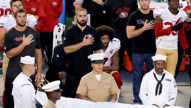 San Francisco 49ers quarterback Colin Kaepernick, middle, kneels during the national anthem before the team's NFL preseason football game against the San Diego Chargers, Green Beret Nate Boyer, who has met with Kaepernick, is at the quarterback's left.