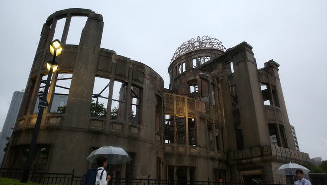 People walk in the rain in front of an Atomic Bomb Dome at the Hiroshima Peace Memorial Park on Aug. 6, 2014, in Hiroshima, Japan.