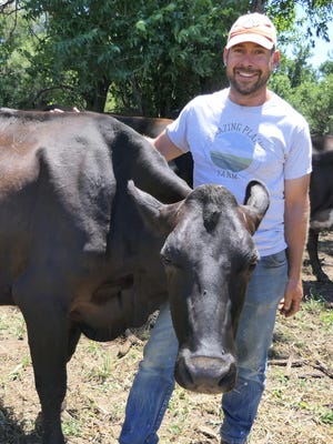 Jason Schmidt and his dairy cow, Buffalo, at Grazing Plains Farm in Newton.