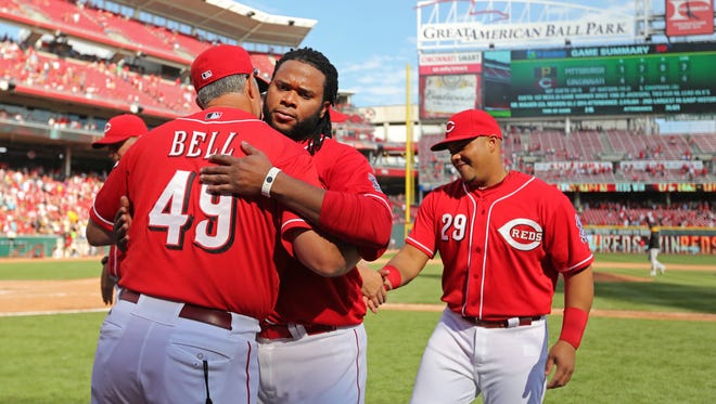 Reds pitcher Johnny Cueto is congratulated by bench coach Jay Bell after winning his 20th game of the 2014 season on Sept. 28.