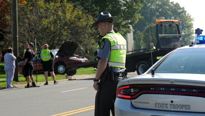 An Ohio Highway Patrol trooper talks on his cell phone Monday morning, Sept. 18, 2017, at the scene of a two-vehicle crash on West Fair Avenue in Lancaster. According to OHP officers at the scene, a blue Ford F-150 went left of center striking a maroon Chevrolet Malibu killing the driver of the smaller car.