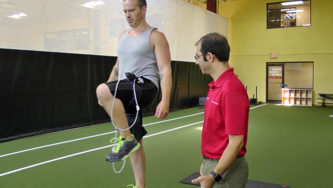 Cameron Steer, a personal trainer with Gold’s Gym, undergoes blood flow restriction therapy on his lower extremities while doing step-up exercises as directed by physical therapist Justin Feldman.