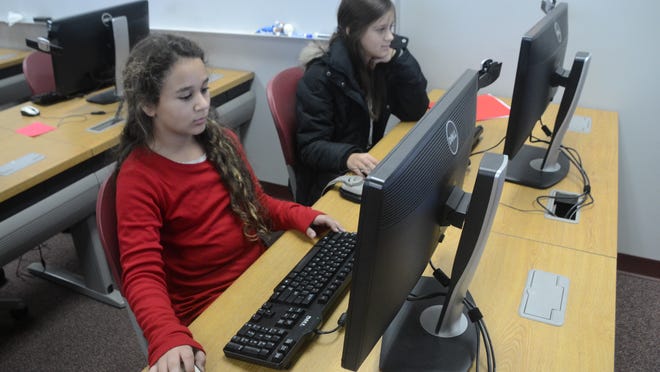 Alexandria Country Day School sixth-graders Amira Benghozi (left) and Mikayla Bayonne work on reports about the Plains Indians. The school is offering Microsoft programs for free to students and parents on up to five devices.
