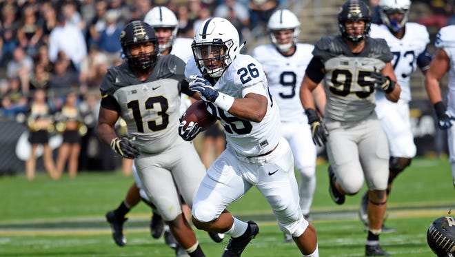 Penn State running back Saquon Barkley (26) runs past Purdue defensive end Gelen Robinson (13) and defensive end Evan Panfil (95)in the first half at Ross Ade Stadium.