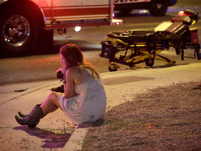 A woman sits on a curb at the scene of the shooting.