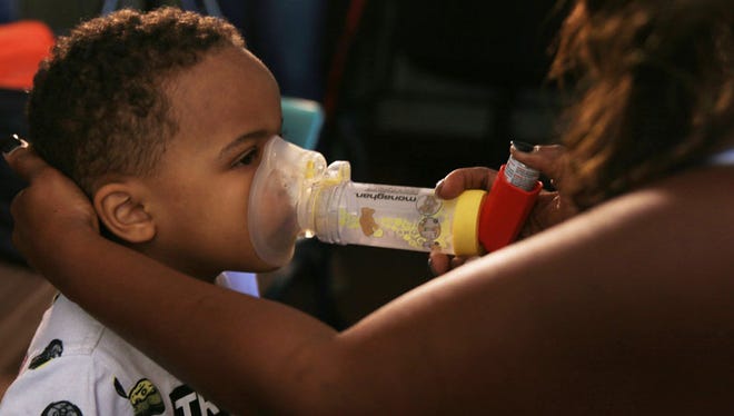 Lassandra Scott helps her four-year-old son, Zaviyon, use his inhaler just seconds after he was wheezing.