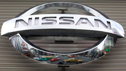 In this 2012 file photo, vehicles are reflected on the logo of the Nissan Motors Co. at a showroom in Tokyo's Ginza shopping district.