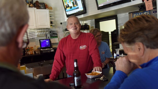 Jon Bot (center), owner of Botski's Bar and Grill, talks with regulars during happy hour on Friday. 