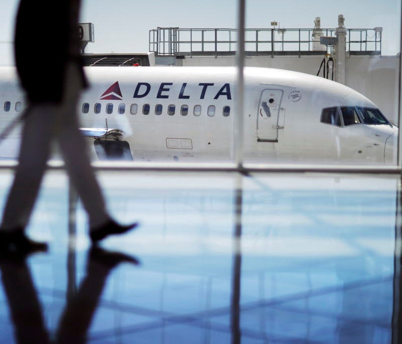 A Delta Air Lines jet sits at a gate at Hartsfield-Jackson Atlanta International Airport in Atlanta as a passenger walks past on Oct. 13, 2016.
