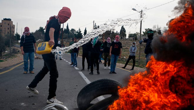 A Palestinian protestor set tires on fire as they build a barricade during clashes with Israeli security forces on Dec. 19, 2017. 