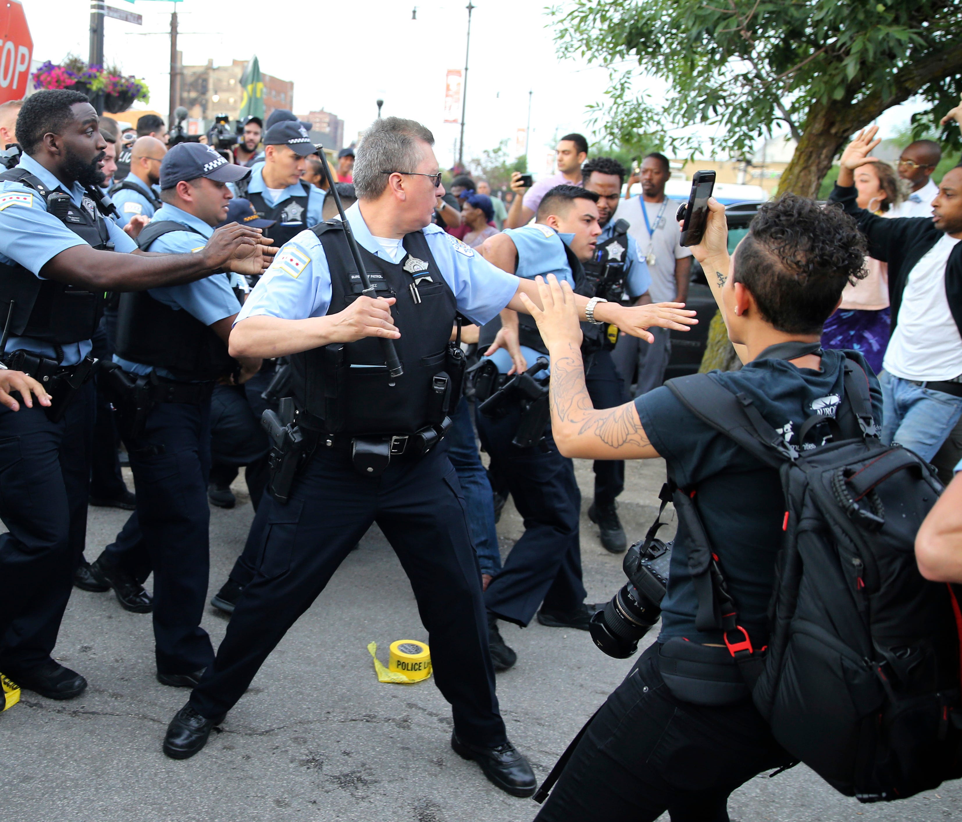 Members of the Chicago police department scuffle with an angry crowd at the scene of a police-involved shooting in Chicago, on Saturday, July 14, 2018.
