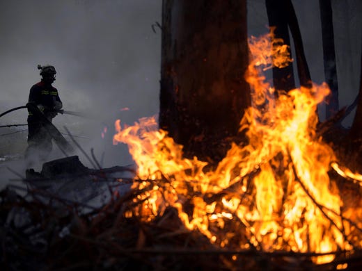 Firefighters try to extinguish a fire raging through