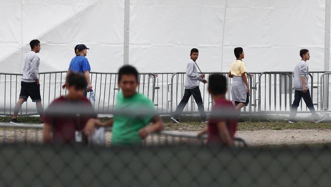 Migrant teens and a staff member walk in a line at the Homestead Temporary Shelter for Unaccompanied Children, a former Job Corps site that now houses them, in Homestead, Fla., on Monday, Dec. 10, 2018. (AP Photo/Brynn Anderson)