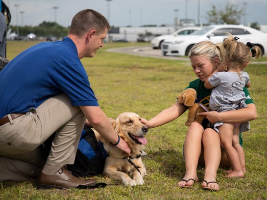 A woman pets a comfort dog at the makeshift memorial