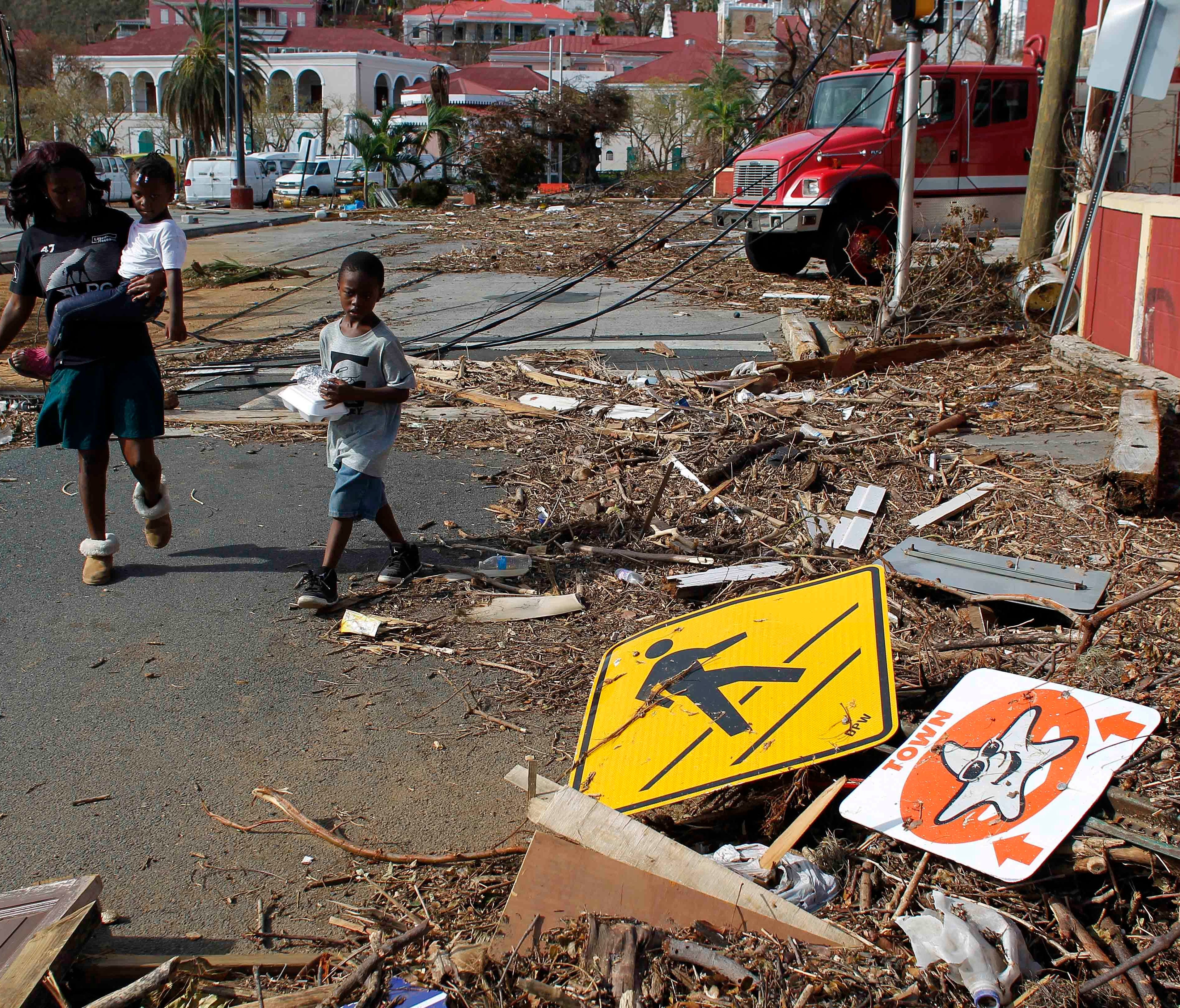A woman with her two children walk past debris left by Hurricane Irma in Charlotte Amalie, St. Thomas, U.S. Virgin Islands, on Sept. 10, 2017.