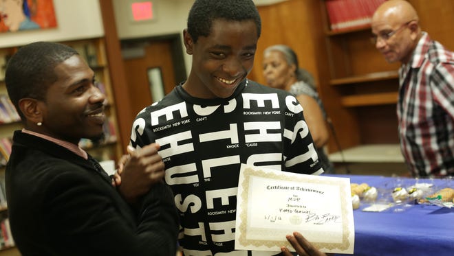 Eighth-grade teacher Olafemi Bankole Akintunde congratulates his student Keeto Gaines, 14, for a good school year in his Manhood Development Program at Westlake Middle School in Oakland, Calif. in June 2016.