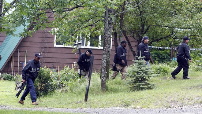 State Police officers search a residential area on Sunday, June 28, 2015, in Malone, N.Y. The shooting death of one escaped killer brought new energy to the three-week hunt for a second escaped murderer in the United States as helicopters, search dogs and hundreds of law enforcement officers converged on a wooded area 30 miles from Clinton Correctional Facility. (AP Photo/Mike Groll)