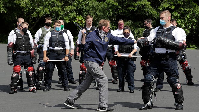 In this June 4, 2020 photo, Christopher Clarke, front left, an instructor at the Washington state Criminal Justice Training Commission facility in Burien, Wash., teaches a class on the use of batons to law enforcement officers as part of the more than 700 hours of training police and other officers are required to go through in the state. Police training has been under scrutiny again since the death of George Floyd, a black man who died after being restrained by Minneapolis police officers.