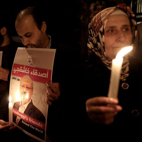 Protestors hold candles and pictures of Jamal...