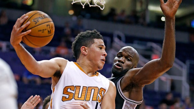 Phoenix Suns' Devin Booker, left, looks to pass the ball against San Antonio Spurs' Joel Anthony during the second half of an NBA preseason basketball game Monday, Oct. 3, 2016, in Phoenix. The Suns won 91-86. (AP Photo/Ross D. Franklin)