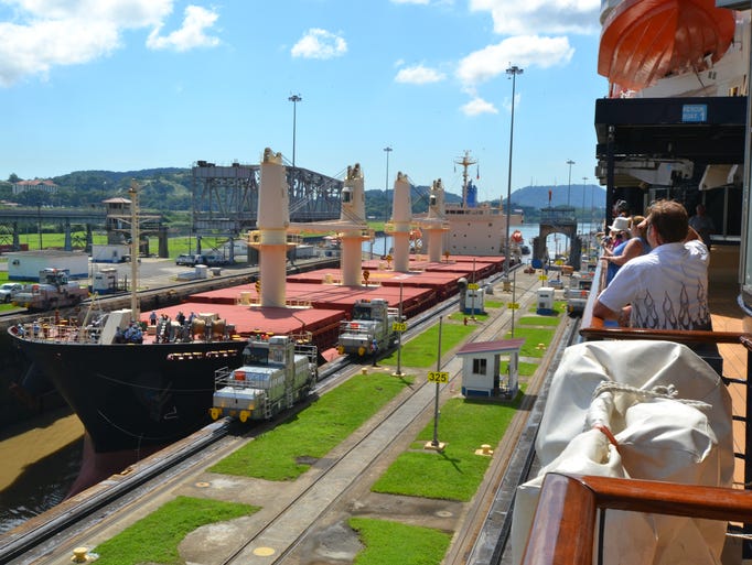 A giant cargo ship enters a lock chamber alongside the Celebrity Millennium at the Panama Canal's Miraflores Locks.