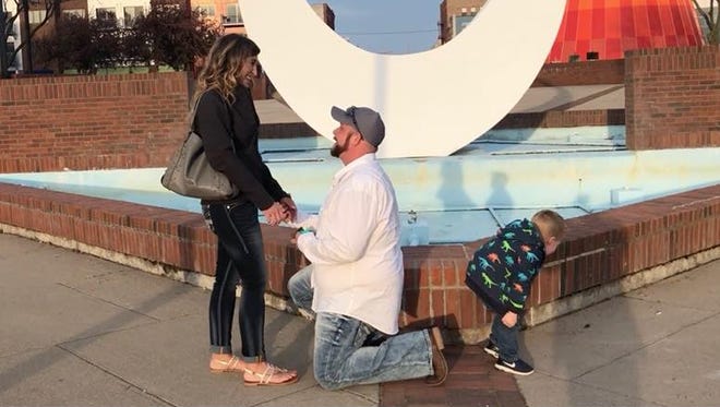 Kevin Przytula, center, proposes to his girlfriend Allyssa as her son Owen, right, decides to pee in a screengrab of a viral video out of downtown Bay City.