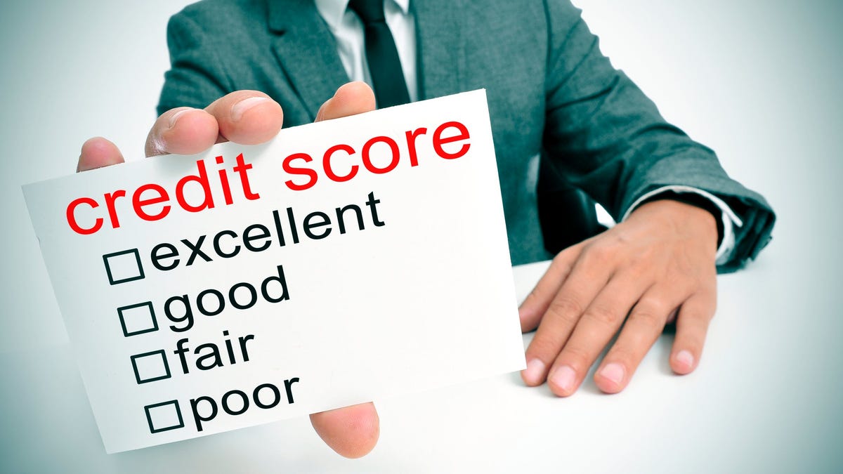 We see part of a man in a suit, holding forward a card on which is printed credit score and the words excellent, good, fair, and poor, with boxes to check next to them.