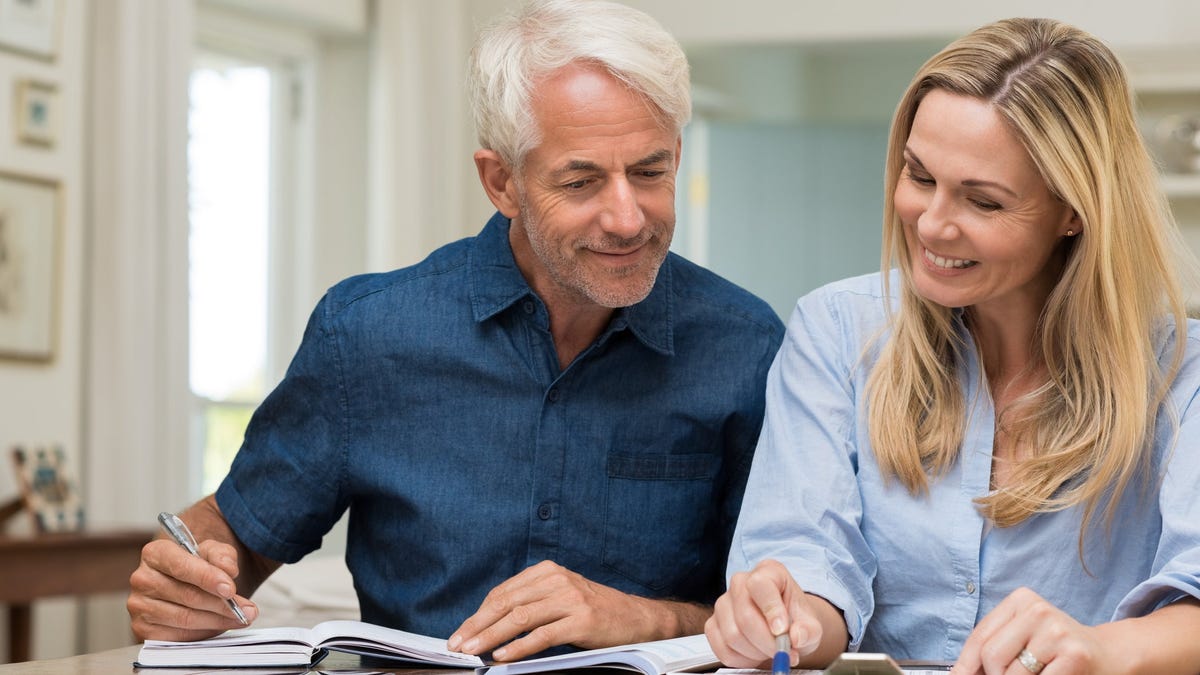 Mature couple smiling and looking at documents.