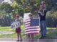 Spectators display signs and a flag along the procession