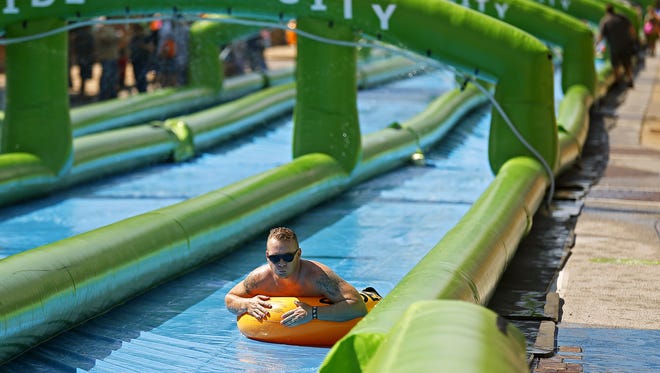 A man zips down Slide the City's giant water slide in downtown Springfield, Mo. on July 16.