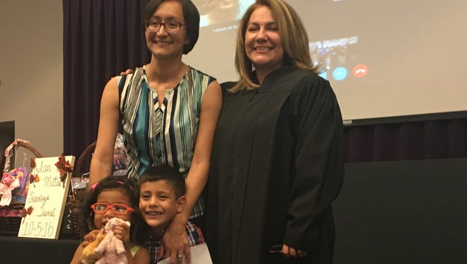 Ana Santiago (top left) stands with her daughter Asia Santiago (bottom left) and son Ian Santiago (bottom right) after Judge Yahara Gutierrez (top right) ordered the adoption be granted during a ceremony Wednesday at the 2016 CARE Conference.