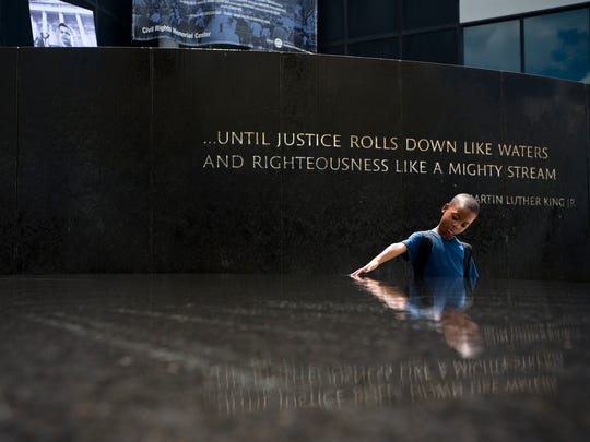 Benjamin Levett, 6, runs his hands through the fountain of the Civil Rights Memorial during a memorial honoring civil rights leader Julian Bond held at the Southern Poverty Law Center in Montgomery, Ala. On Saturday, Aug. 22, 2015.