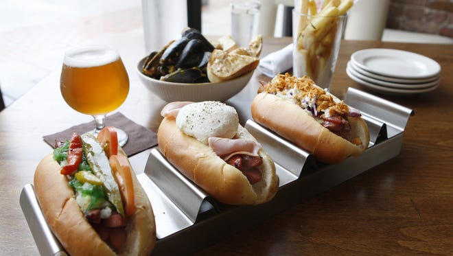 A photo of the Chicago hot dog, Croque Madame hot dog and Trailer Park hot dog with a side of mussels charmoula and duck fat fries to be washed down with a la chouffe, a Belgian pale ale, from Senate, in Over-the-Rhine.