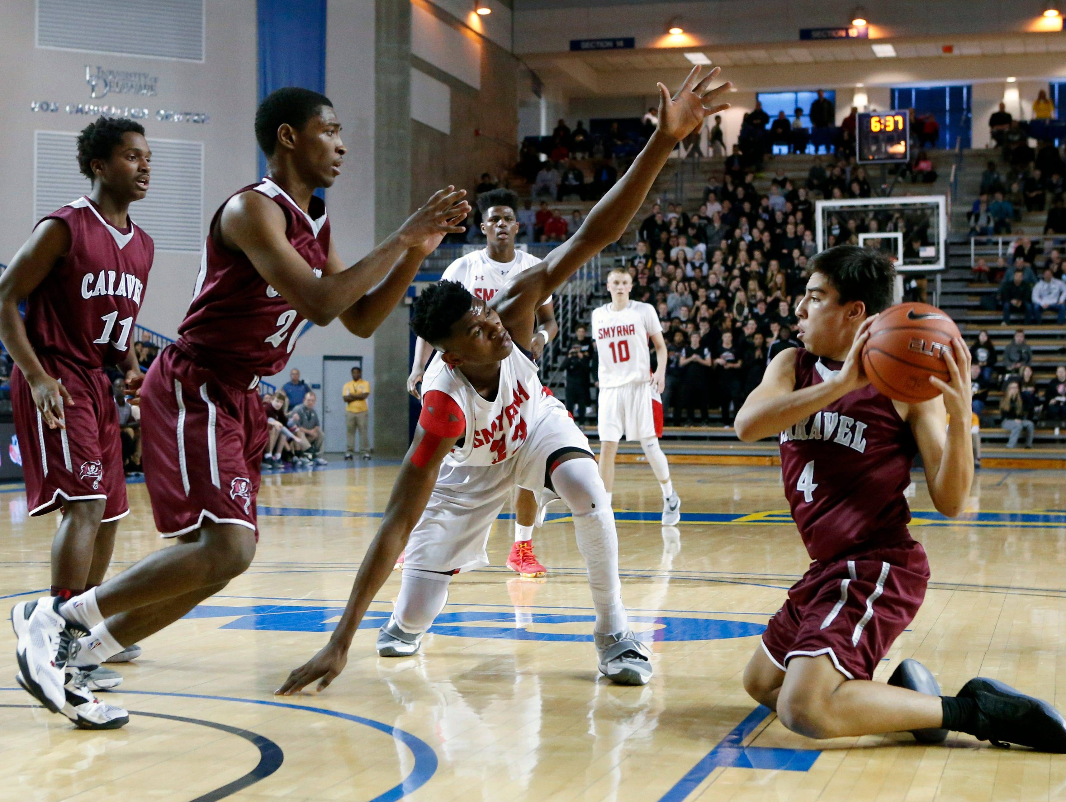 Caravel's Brandon Sengphachanh snags a loose ball in front of Smyrna's Zubi Nwankwo and teammates Mandela Montgomery (left) and Trevon Alderman in the second half of the Eagles' 61-53 win in the DIAA state tournament title game at the Bob Carpenter Center Saturday.