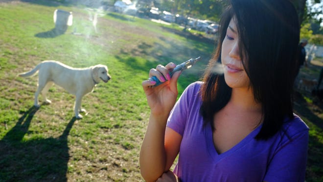 
Christine Choi takes a puff on her e-cigarette at the Sepulveda Basin Dog Park in Los Angeles. Recent surges in the use of e-cigarettes and chewing tobacco has raised questions about those products on pets. The greatest danger is the trash. Despite how rancid they seem to us, dogs will eat discarded batteries and cartridges from e-cigarettes.

