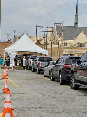 People in their vehicles wait in line to get tested for COVID-19 at Shannon Medical Center, at 110 E. Twohig Street. This was the first stop, where a Shannon Medical Center nurse took your vitals and wrote down your personal information.