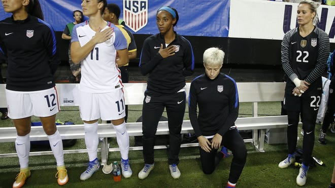 In this Sept. 18, 2016, photo, United States' Megan Rapinoe kneels as the national anthem is played before the team's exhibition soccer match against the Netherlands in Atlanta. The U.S. women's national team wants the U.S. Soccer Federation to repeal the anthem policy it instituted after Rapinoe started kneeling during the national anthem. The U.S. women's team also wants the federation to state publicly that the policy was wrong and issue an apology to the team's black players and supporters.