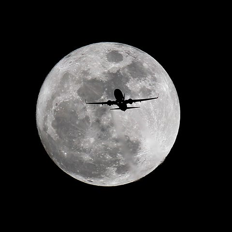 A commercial airliner crosses the first full Moon 